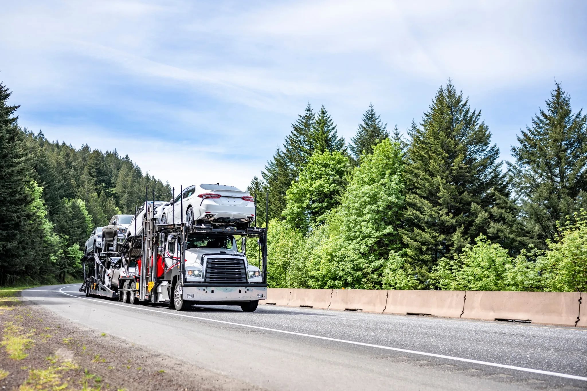 Open carrier transporting multiple vehicles for door to door delivery open car carrier transporting sedans on a highway for nationwide door to door auto transport